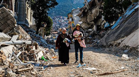 Eine Frau und ein junger Mann gehen durch die Trümmer des verheerenden Erdbebens in der Türkei