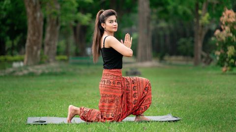 Eine Frau macht Yoga auf einer Wiese