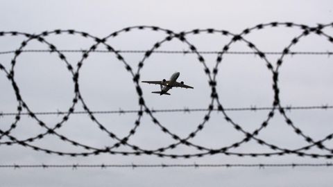 Ein Flugzeug startet - fotografiert durch Stacheldraht am Flughafenzaun