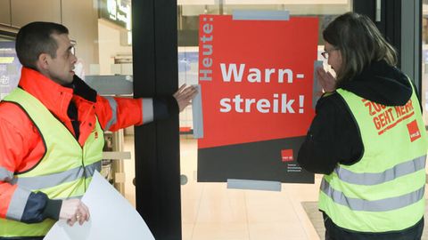 Am Flughafen Hamburg bringen Mitarbeiter ein Plakat mit der Aufschrift "Heute: Warnstreik" an