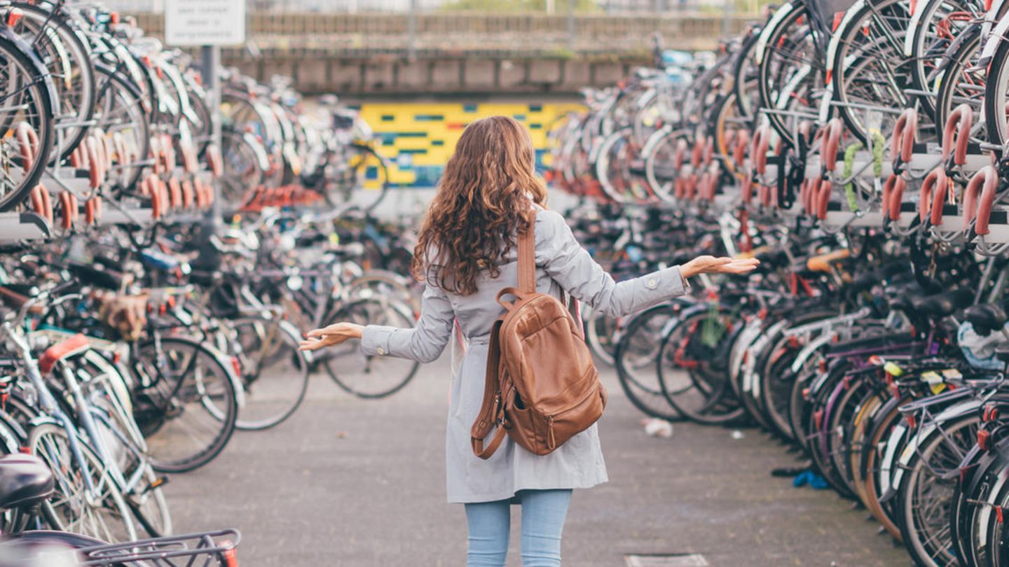 Frau zwischen Fährrädern in Fahrradparkplatz