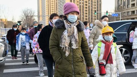Eltern bringen ihre Kinder in Peking zur Grundschule. Die meisten tragen Maske.