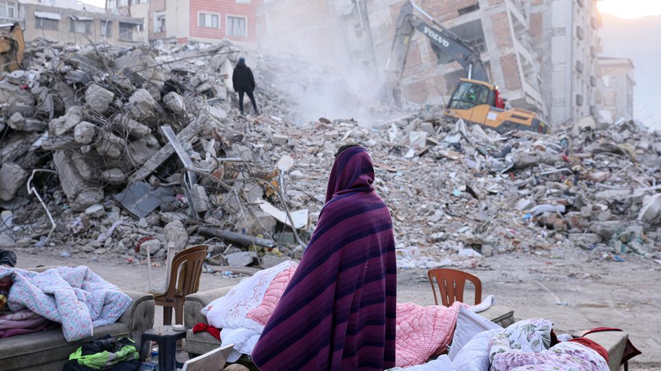 Türkei Syrien Erdbeben Eine Frau steht vor den Trümmern ihres Hauses in der türkischen Stadt Hatay