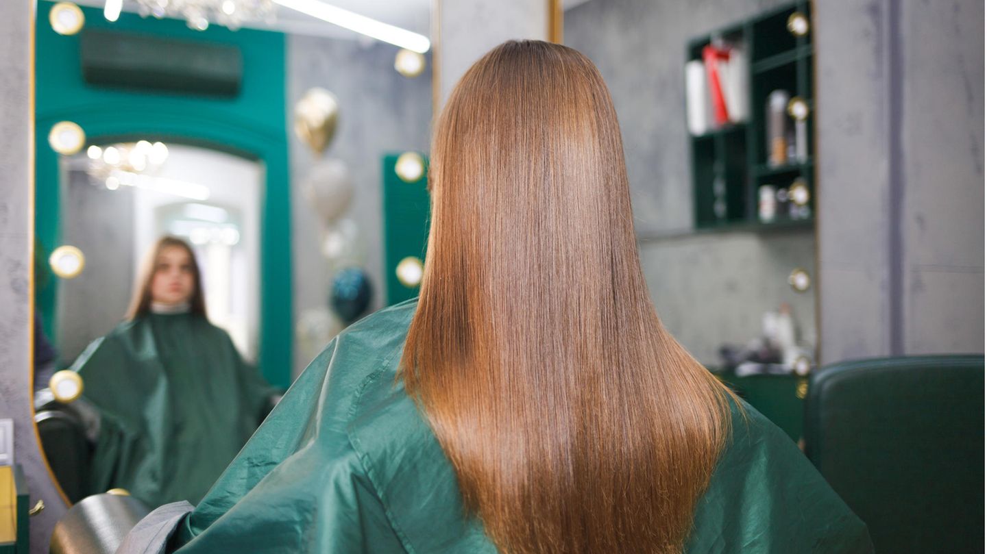 Eine Frau hat glänzende, lange Haare und sitzt beim Friseur.