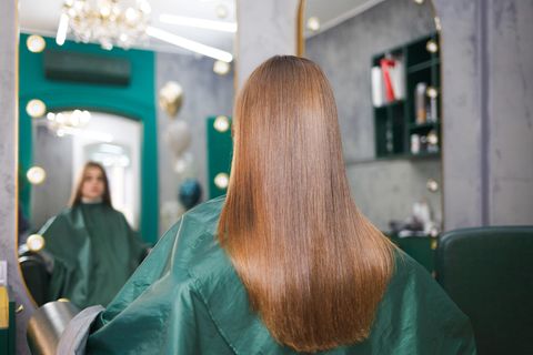 Eine Frau hat glänzende, lange Haare und sitzt beim Friseur.