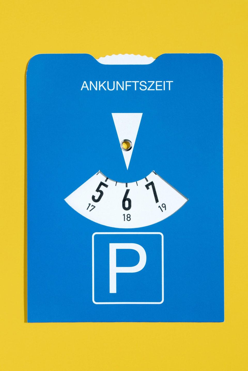 Eine blaue Parkscheibe vor gelbem Hintergrund