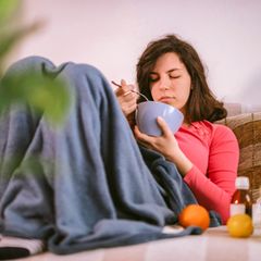 Frau mit Erkältung, die Hühnersuppe isst Frau mit Erkältung, die Hühnersuppe isst