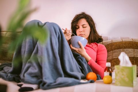 Frau mit Erkältung, die Hühnersuppe isst