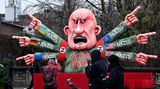 Ein Mann fotografiert einen Karnevalswagen mit Russlands Präsident Wladimir Putin als Motiv