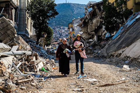 Türkei, Hatay: Eine Frau und ein junger Mann gehen durch die Trümmer des verheerenden Erdbebens vom 6. Februar (Foto vom 12. Februar)
