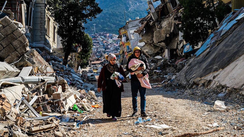 Türkei, Hatay: Eine Frau und ein junger Mann gehen durch die Trümmer des verheerenden Erdbebens vom 6. Februar (Foto vom 12. Februar)