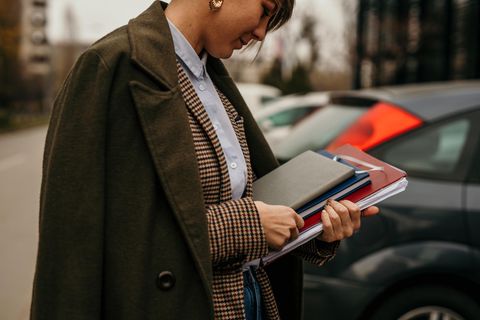 Eine Frau im Look des Dark Academia Style hält Bücher in der Hand.