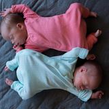 Zwilinge in blau und rosa Strampelanzügen