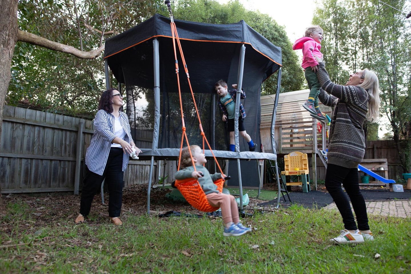 Sharon mit ihrer Partnerin und den drei Kindern beim Spielen im Garten Sharon mit ihrer Partnerin und den drei Kindern beim Spielen im Garten