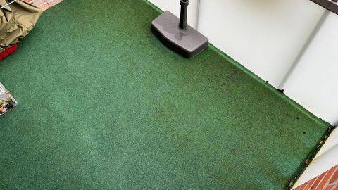 Balkonteppich kaufen und pflegen: Grüne Auslegware liegt auf einem Balkon