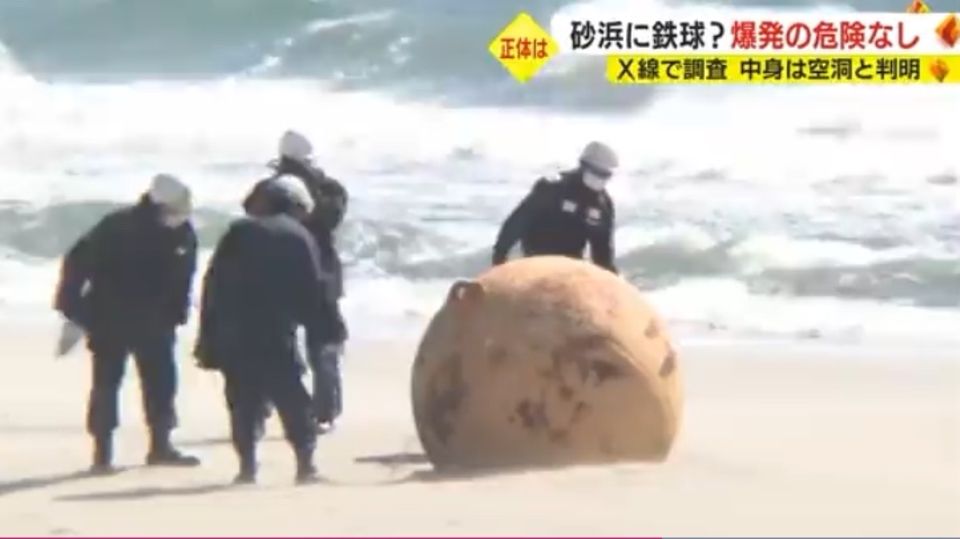 Sicherheitskräfte untersuchen die Metallkugel am Strand von Hamamatsu in Japan
