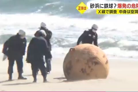 Sicherheitskräfte untersuchen die Metallkugel am Strand von Hamamatsu in Japan