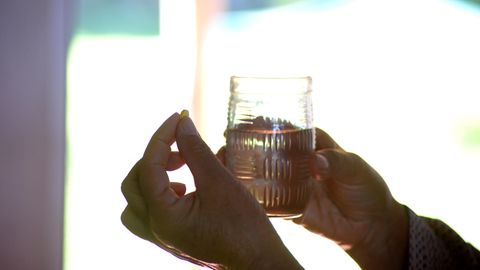 Hände halten ein Glas Wasser und eine Tablette