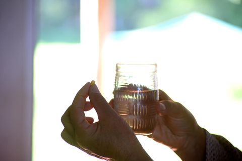 Hände halten ein Glas Wasser und eine Tablette mit Antidepressiva gegen Depressionen