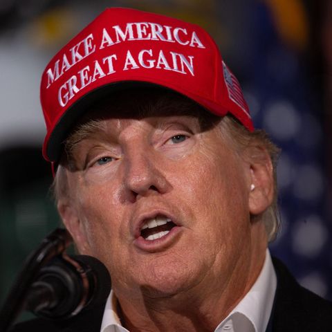 Donald Trump spricht mit roter "Make America great again"-Mütze auf dem Kopf in ein Mikrofon