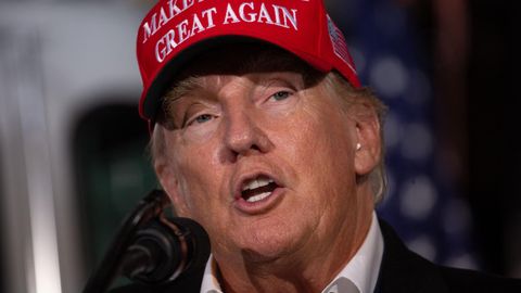 Donald Trump spricht mit roter "Make America great again"-Mütze auf dem Kopf in ein Mikrofon