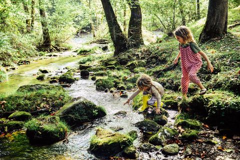 Zwei Kinder spielen am Fluss. "Sittervising" heißt es, wenn Eltern aus der Ferne zuschauen.