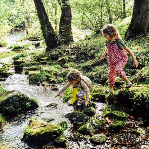 Zwei Kinder spielen am Fluss. "Sittervising" heißt es, wenn Eltern aus der Ferne zuschauen.