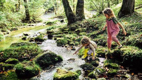 Zwei Kinder spielen am Fluss. "Sittervising" heißt es, wenn Eltern aus der Ferne zuschauen.