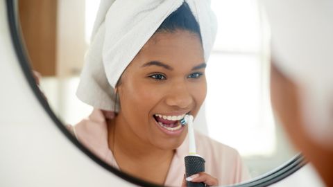 Eine Frau putzt sich die Zähne mit einer elektrischen Zahnbürste.