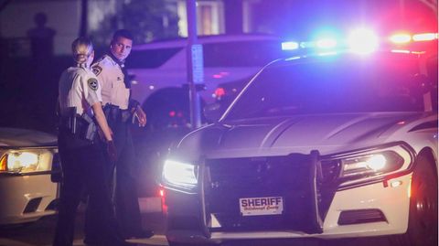 Polizisten stehen in Florida neben einem Polizeiauto