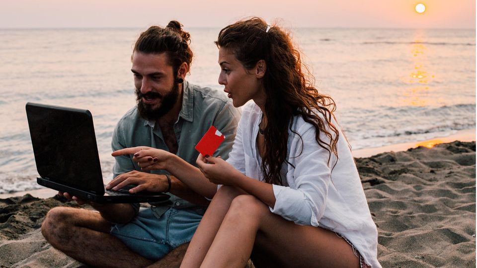 Paar am Strand mit Laptop und Kreditkarte