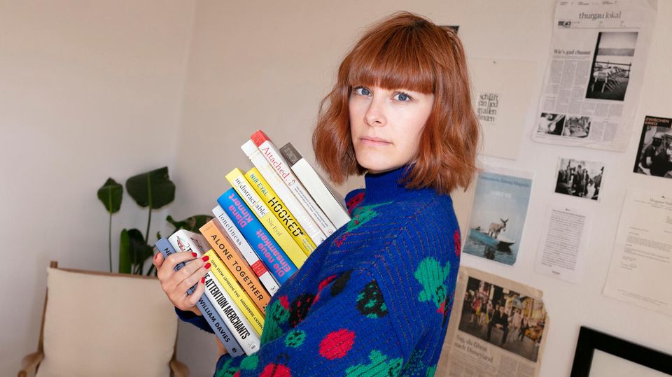 Anna Miller ist Autorin und Expertin für digitale Achtsamkeit. Hier hält sie einen Stapel Bücher in der Hand.