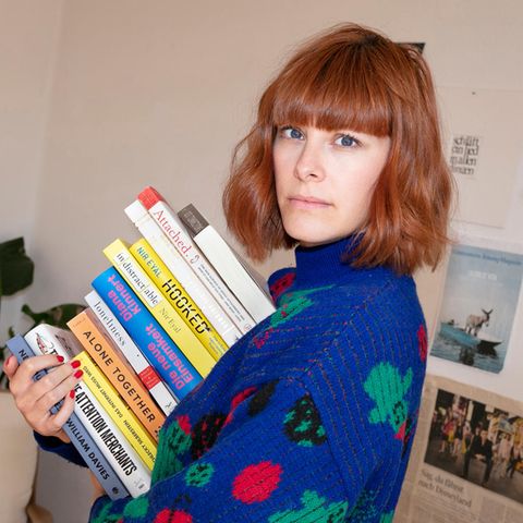 Anna Miller ist Autorin und Expertin für digitale Achtsamkeit. Hier hält sie einen Stapel Bücher in der Hand.