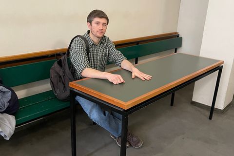 Klimaaktivist Henning Jeschke sitzt festgeklebt an einem Tisch in einem Raum des Amtsgericht Tiergarten
