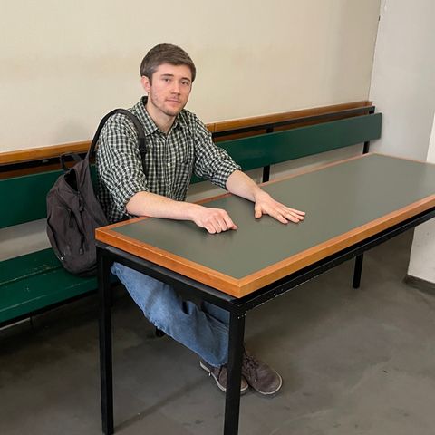 Klimaaktivist Henning Jeschke sitzt festgeklebt an einem Tisch in einem Raum des Amtsgericht Tiergarten