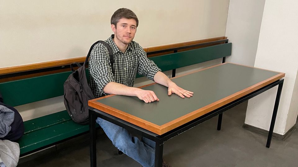 Klimaaktivist Henning Jeschke sitzt festgeklebt an einem Tisch in einem Raum des Amtsgericht Tiergarten