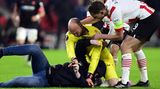 Dmitrovic nimmt den Schläger in die Mangel und Eindhoven-Profis eilen hinzu, um den Keeper von Schlimmeren abzuhalten. "Es ist niemals gut, das im Fußball zu sehen, das sollte nicht passieren und ich hoffe, dass diese Dinge bestraft werden", sagt Dmitrovic zu dem Angriff. "Ich kann mir vorstellen, dass er sauer wegen des Ergebnisses von PSV war. Wenn mich jemand angreift, verteidige ich mich. Er hat versucht mich zu schlagen, aber ich konnte ihn festhalten und warten, bis die Sicherheitsleute kommen."