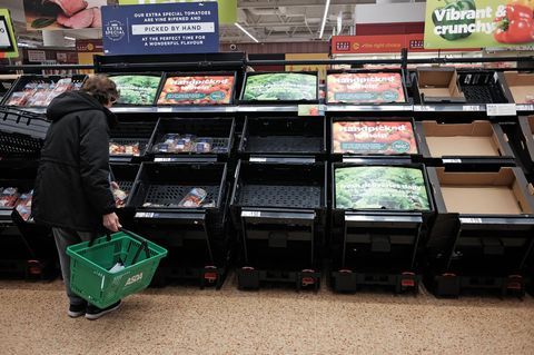 Eine Kundin prüft die fast leeren Obst- und Gemüseregale in einem Supermarkt