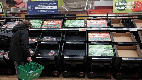 Eine Kundin prüft die fast leeren Obst- und Gemüseregale in einem Supermarkt