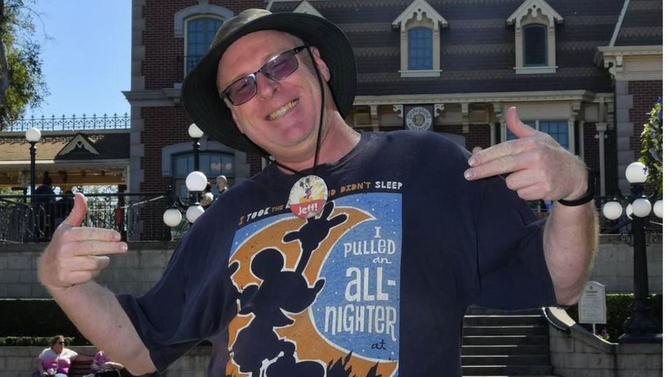Jeff Reitz steht stolz im Disneyland und trägt ein T-Shirt mit einem Motiv des Vergnügungsparks