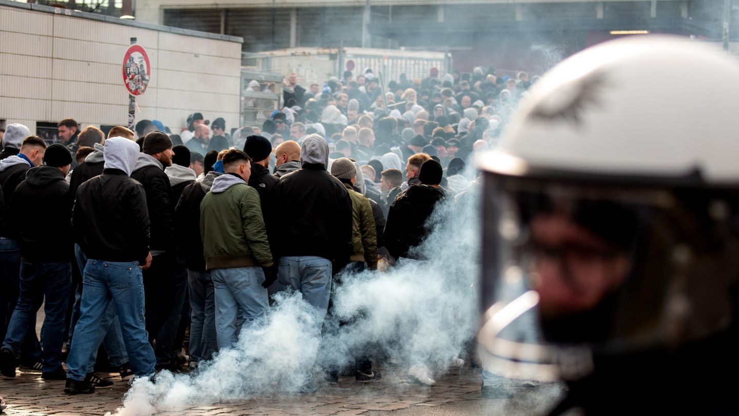 Rostocks Fans gehen an brennender Pyrotechnik vorbei ins Stadion.