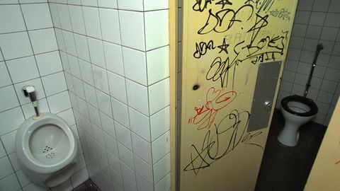 Eine Tür an einer Schultoilette, die mit Graffiti vollbesprüht ist (Symbolbild)