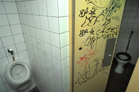 Eine Tür an einer Schultoilette, die mit Graffiti vollbesprüht ist (Symbolbild)