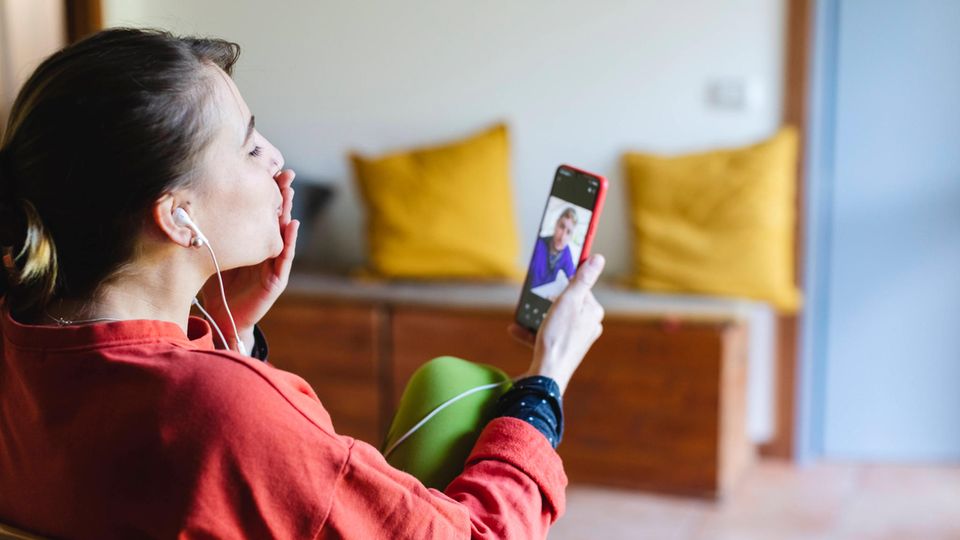 Frau deutet mit der Hand am Mund einen Kuss während eines Videotelefonats an