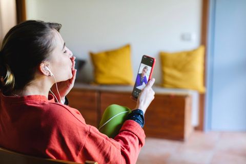 Frau deutet mit der Hand am Mund einen Kuss während eines Videotelefonats an