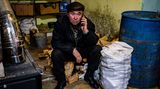 Bachmut, Ukraine. Ein älterer Mann sitzt auf einem Stapel Holz und telefoniert mit einem humanitären Hilfszentrum. Im Osten der Ukraine tobt ein erbitterter Abnutzungskrieg. Die Schlacht um Bachmut ist der bisher längste Kampf im Ukraine-Krieg.