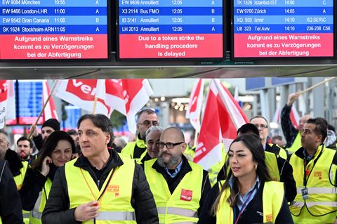 Streikende Flughafen-Mitarbeiter stehen mit Verdi-Flaggen im Terminal des Flughafens in Düsseldorf 