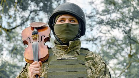 Ukrainischer Soldat spielt mit seiner Violine im Kriegsgebiet
