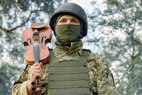 Ukrainischer Soldat spielt mit seiner Violine im Kriegsgebiet