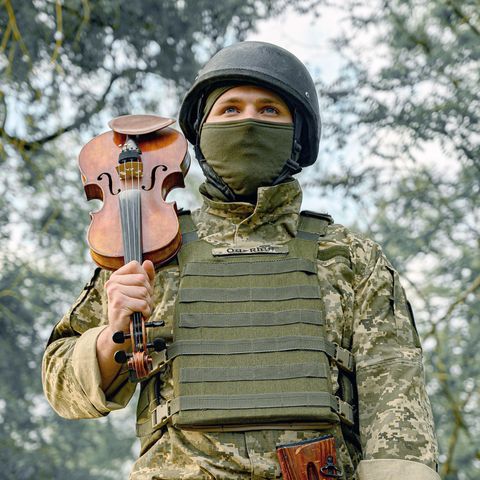 Ukrainischer Soldat spielt mit seiner Violine im Kriegsgebiet